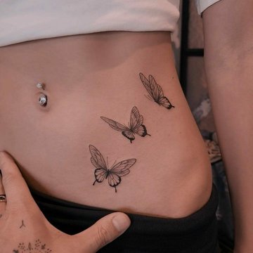 kobiecy tatuaż na brzuchu z realistycznym motylem w stylu fine line